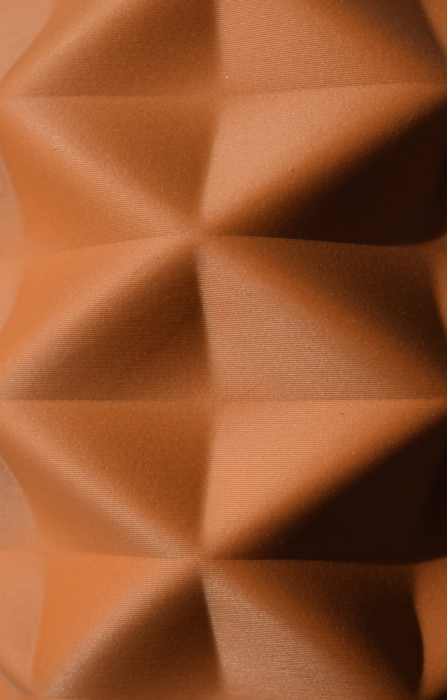 Nahaufnahme einer beige 3D-gedruckten Oberfläche in Terrakotta Lehmbraunoptik mit Geometrischer Pyramidenstruktur.