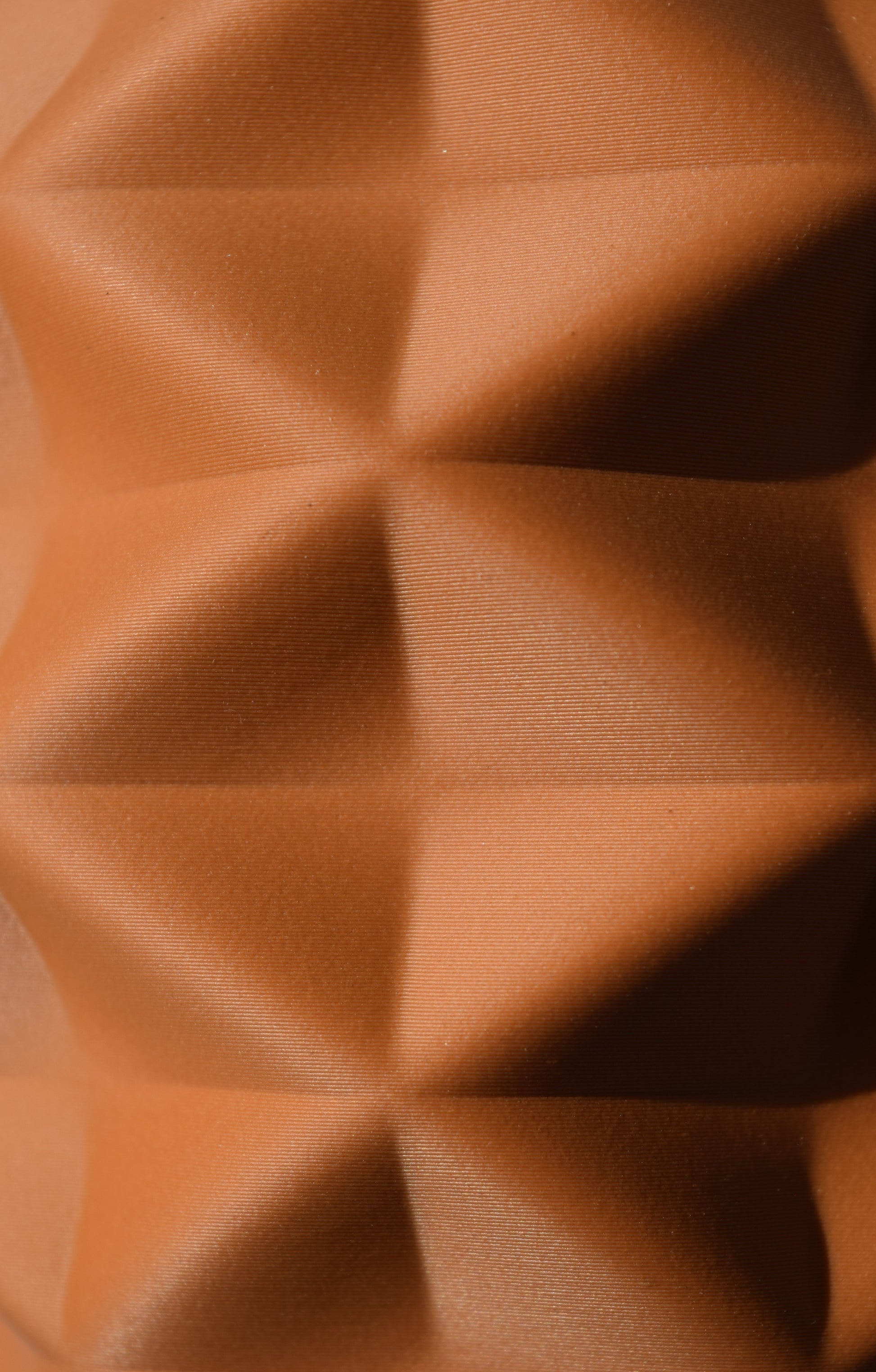 Nahaufnahme einer beige 3D-gedruckten Oberfläche in Terrakotta Lehmbraunoptik mit Geometrischer Pyramidenstruktur.