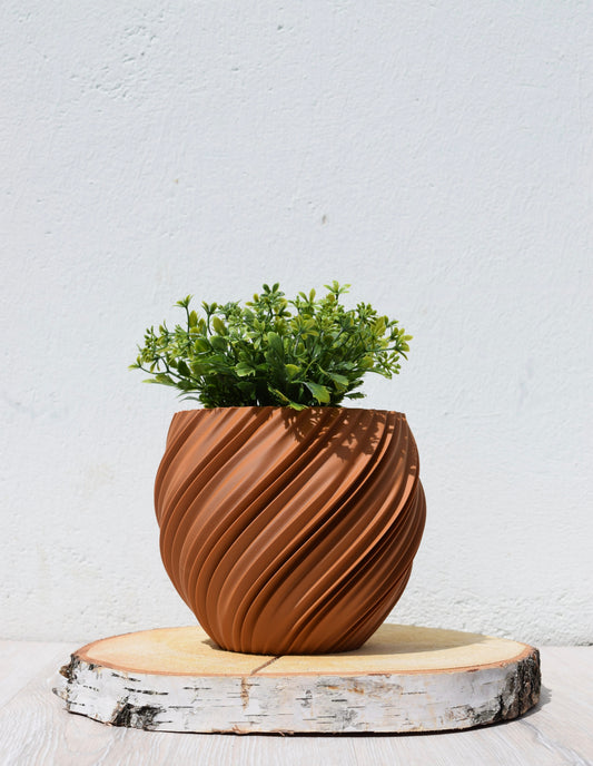 Moderner, runder Blumentopf mit geschwungenem Spiraldesign und mattierter Oberfläche, gefertigt im 3D-Druck-Verfahren. 

Farbe Lehmbraun (Terrakotta).

Das Zeitlose, minimalistische Design verschönert dein Zuhause ,Büro oder Fensterbank